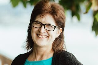 A woman wearing glasses and smiling for the camera.