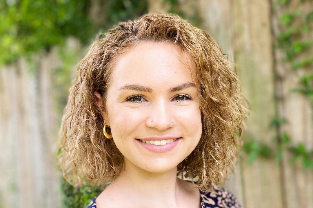 A woman with curly hair wearing a leopard print shirt.