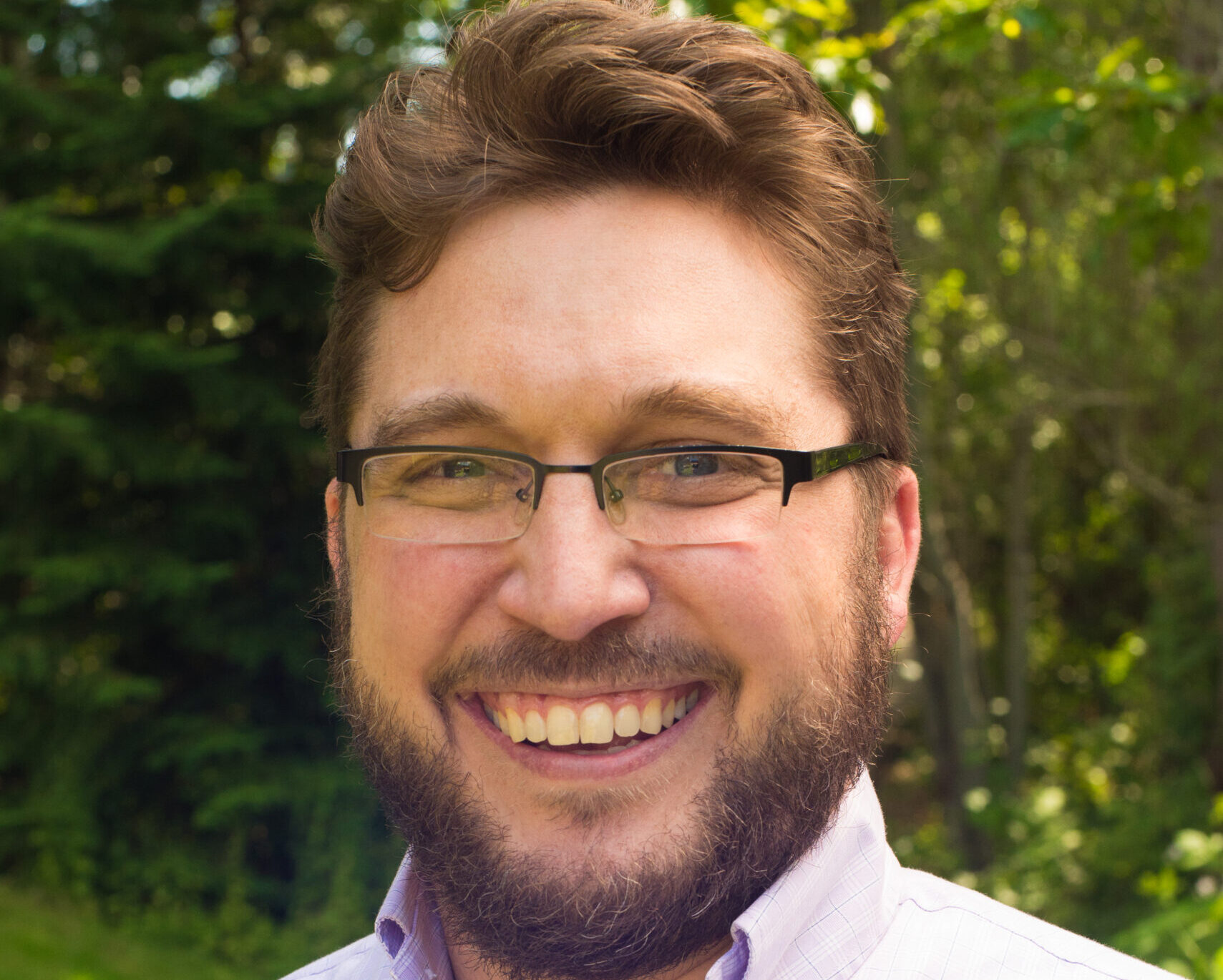 A man with glasses smiling for the camera.