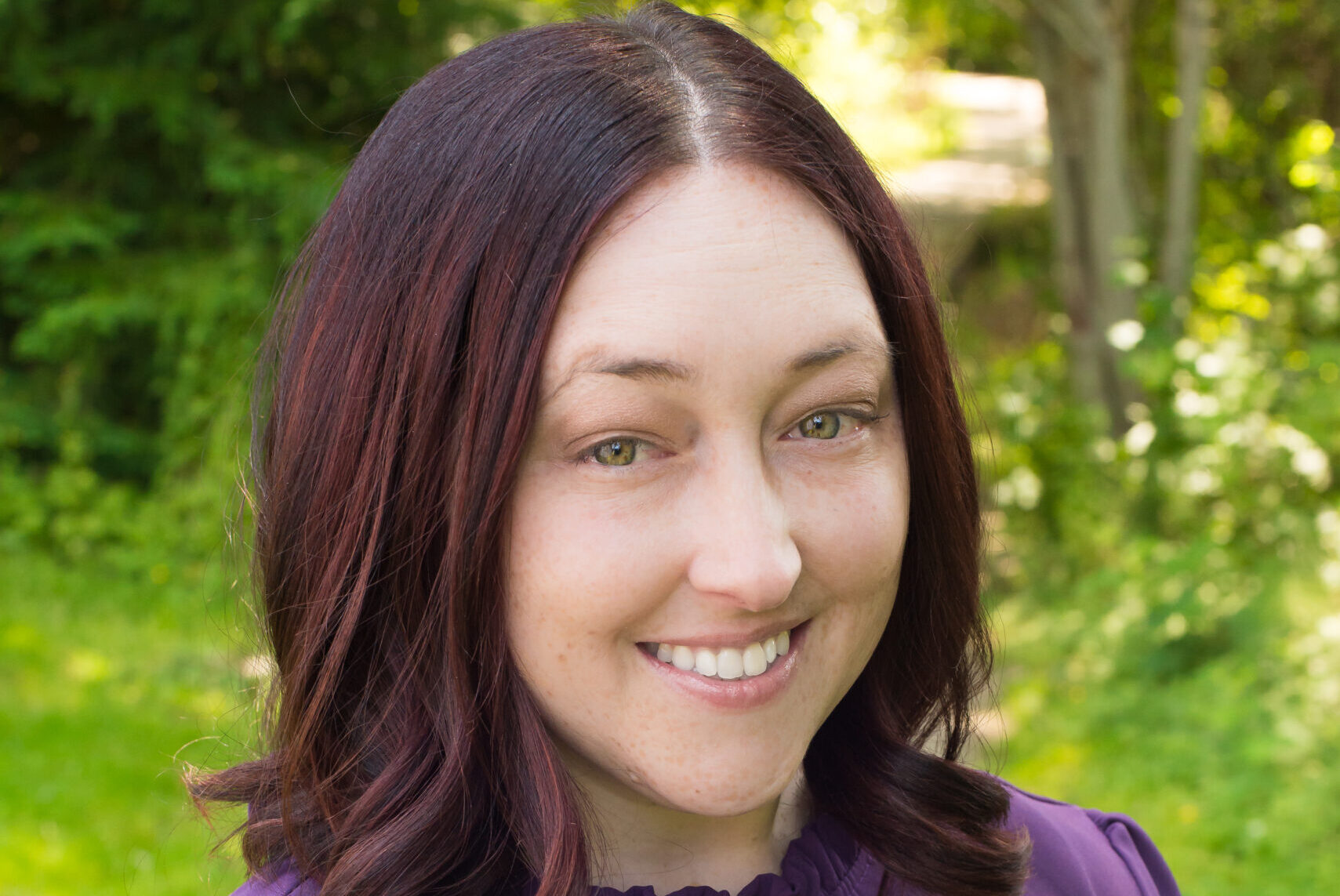 A woman in purple shirt smiling for the camera.