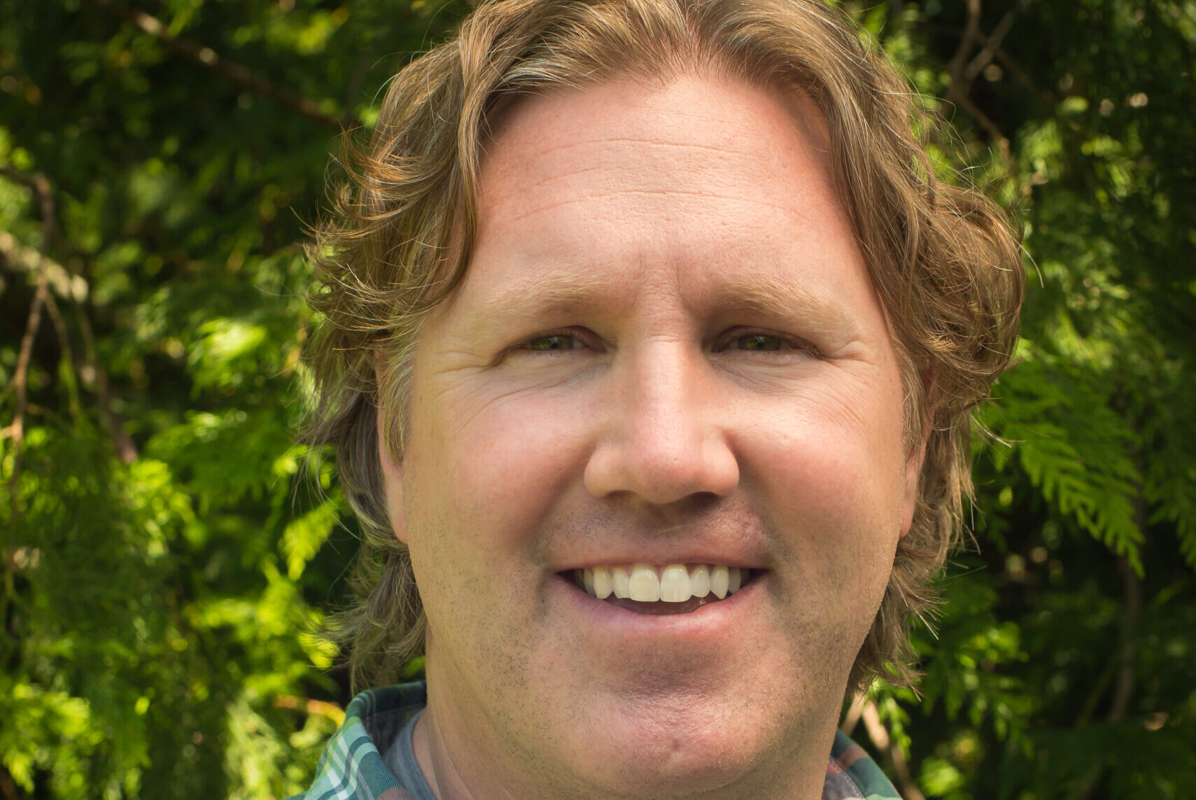 A man in plaid shirt smiling for the camera.