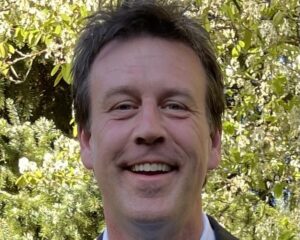 A man in suit and tie smiling for the camera.