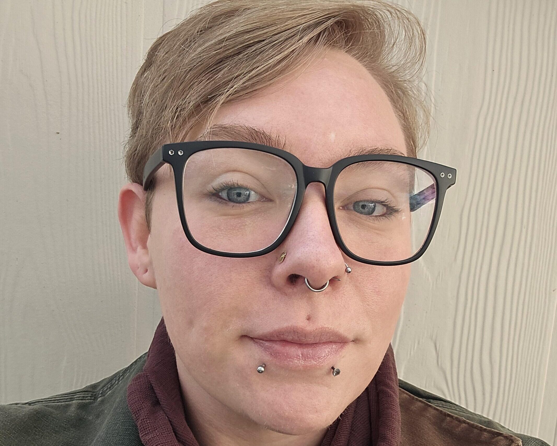 A woman with glasses and a brown jacket.